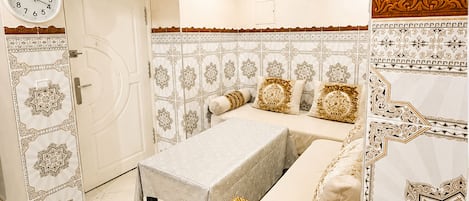 A bedroom with a bed, a bedside table, a clock, and patterned wall decorations.