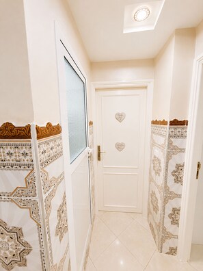 A hallway with a white door, patterned wall designs, and a ceiling light. - Airport Comfort Tanger – Apartment (Tanger)