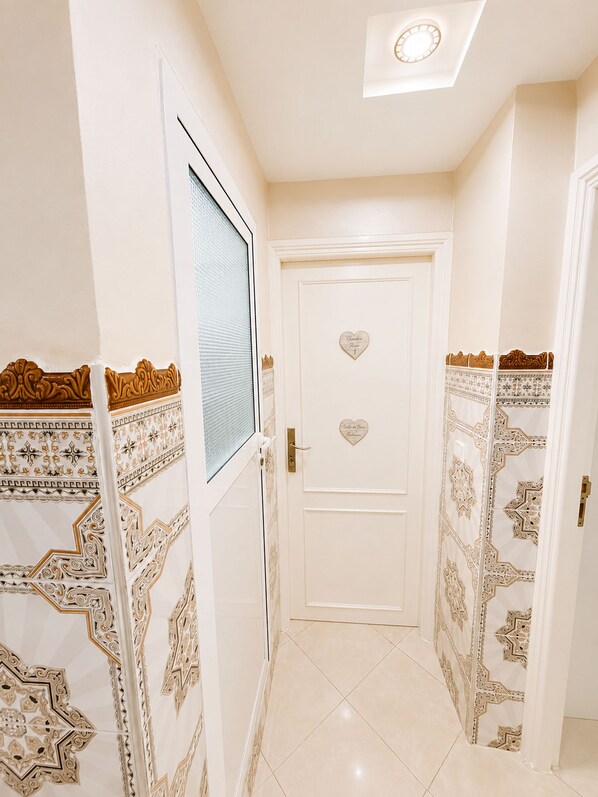 A hallway with a white door, patterned wall designs, and a ceiling light. - Airport Comfort Tanger – Apartment (Tanger)