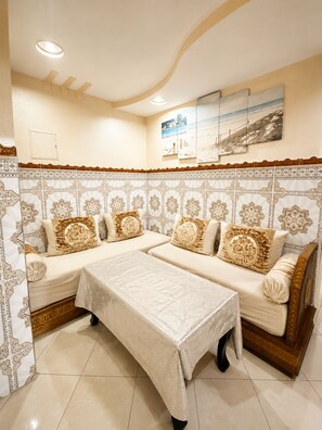 A room with a sofa set, a table, and patterned wall decor. - Airport Comfort Tanger – Apartment (Tanger)