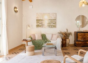 Ein Wohnzimmer mit Sofa, Couchtisch, Lampe, Spiegel und Wanddeko.