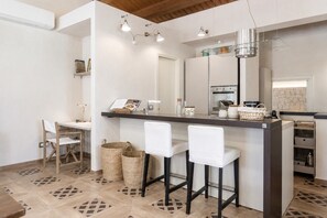Une cuisine moderne dotée d’un îlot central, de tabourets de bar, d’un coin repas avec des chaises et d’un sol à motifs.