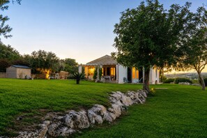 Une maison avec une façade en pierre, un patio couvert et une pelouse bien entretenue.