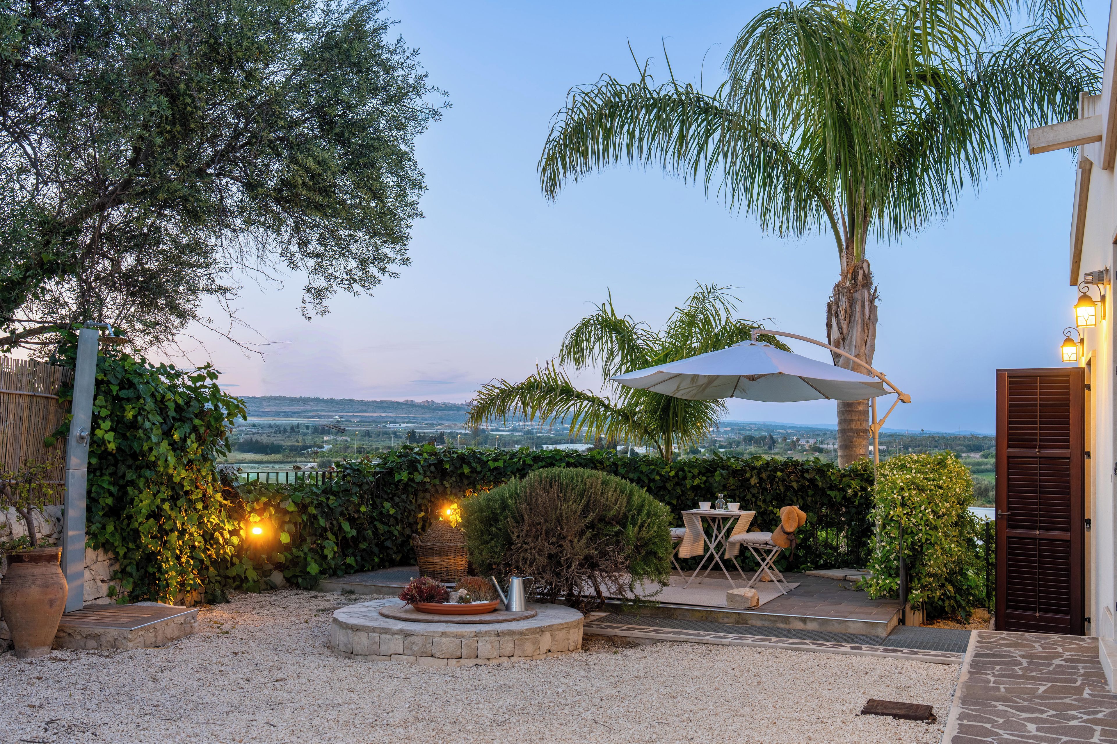 A patio area with a table and chairs, a decorative fire pit, and a view of the landscape.