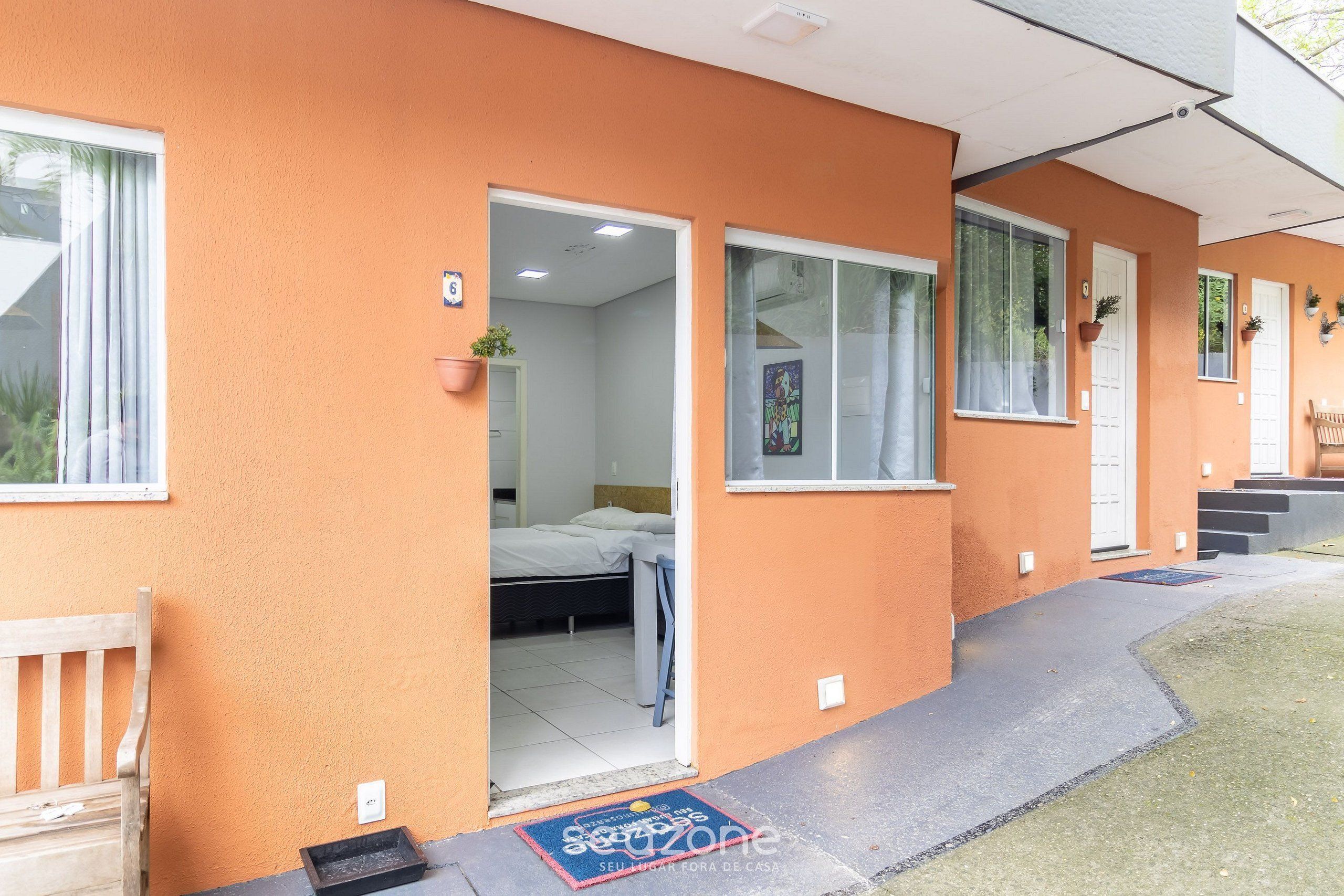 Un edificio de dos pisos con techo plano, una entrada frontal con puerta y un pequeño porche.