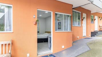 Un edificio de dos pisos con techo plano, una entrada frontal con puerta y un pequeño porche.