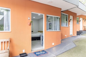 A two-story building with a flat roof, a front entrance with a door, and a small porch area. - Cozy Studio Facing the Lagoon Sdr007 (Florianópolis)