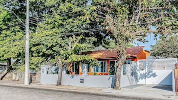 Una propiedad residencial con entrada porticada, un garaje pequeño adosado y una casa con techo rojo.