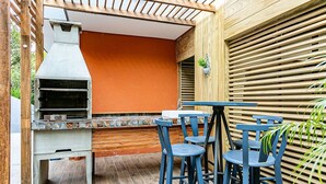 Patio esterno con barbecue, tavolo e sedie blu.