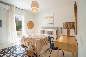 A bedroom with a bed, bedside table, chair, and a view through a glass door. - Villa Marra Sicilymyhome (Noto)