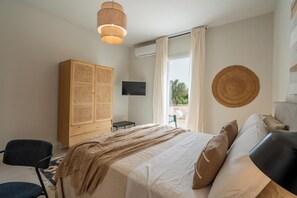 Une chambre à coucher avec un lit, une armoire, une télévision et une vue sur l’extérieur.