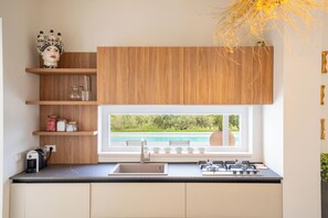 Une cuisine moderne dotée d’une fenêtre intégrée, de meubles en bois, d’une cuisinière à gaz et d’une machine à café.