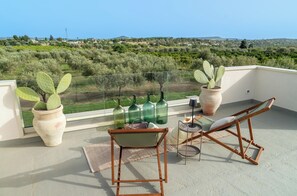 A balcony with a chair, a table, and potted plants. - Villa Marra Sicilymyhome (Noto)