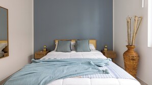 A bedroom with a bed, nightstands, a mirror, and a vase with dried plants. - Marzamemi on the Beach Sicilymyhome (Pachino)