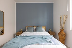 A bedroom with a bed, nightstands, a mirror, and a vase with dried plants. - Marzamemi on the Beach Sicilymyhome (Pachino)