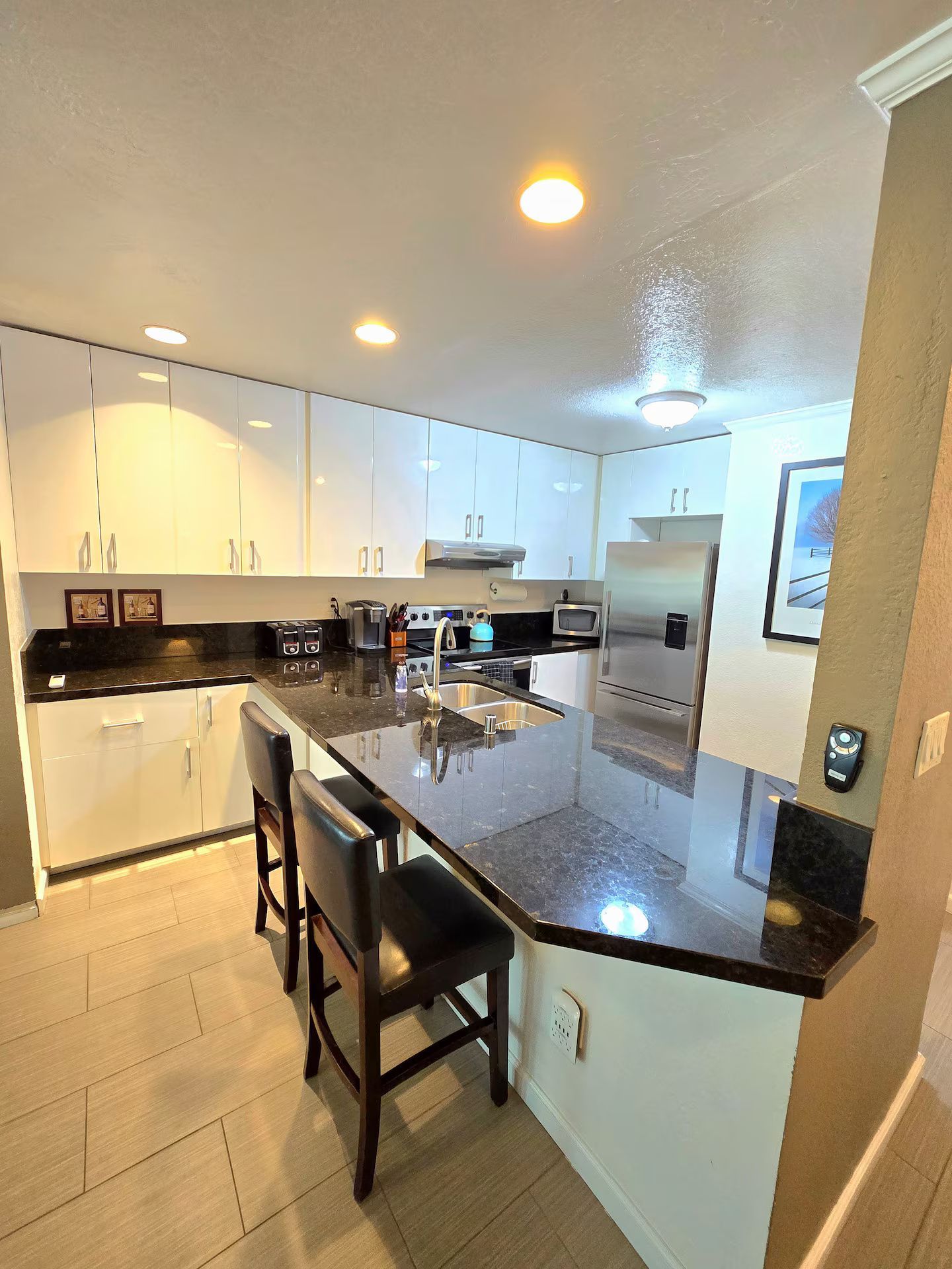 A modern kitchen with white cabinets, a black countertop, and stainless steel appliances.