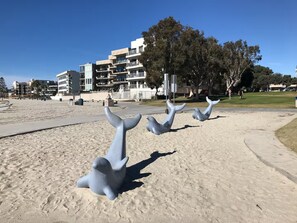 A beach with sculptures of dolphins and a building in the background. - Bay View Condo Near SeaWorld, San Diego (San Diego)