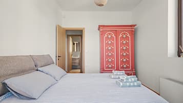 A bedroom with a bed, pillows, a wardrobe, and a hanging light fixture.