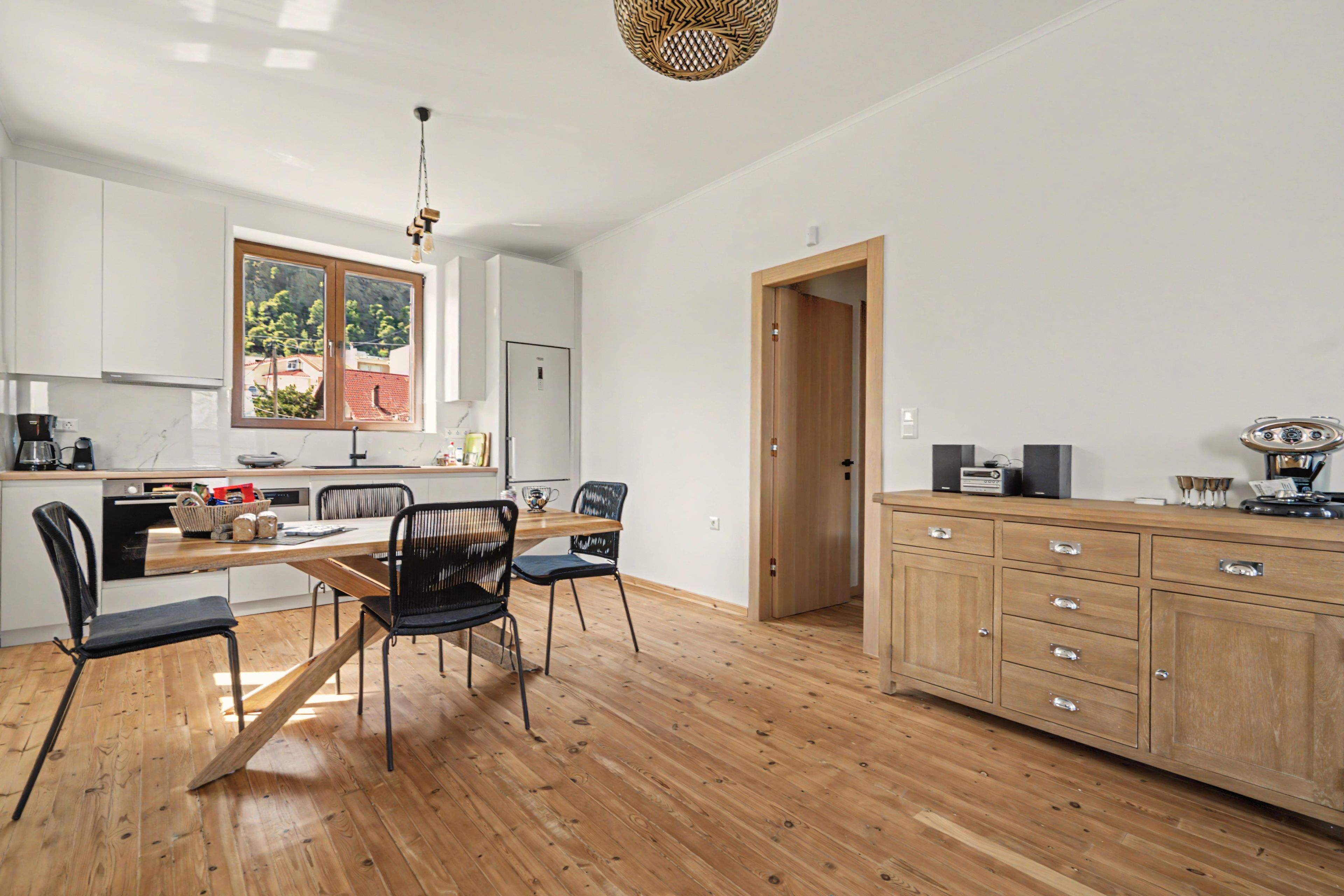 Une cuisine moderne avec un coin repas, des meubles en bois et une vue par la fenêtre.