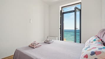 A bedroom with a bed, a window, and a view of the sea.