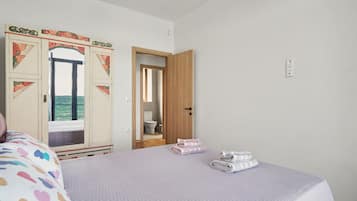 Una habitación con cama, armario y baño visible a través de una puerta abierta.