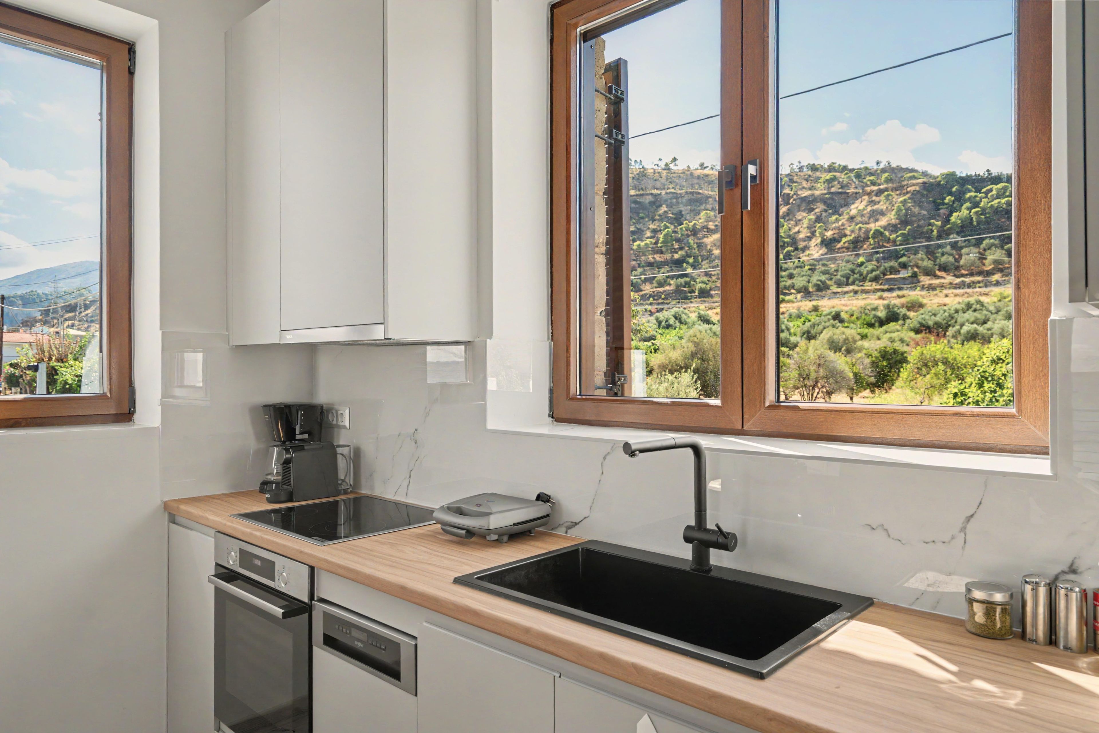 Una cocina moderna con horno empotrado, cafetera y pileta.