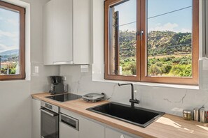 A modern kitchen with a built-in oven, a coffee maker, and a sink.