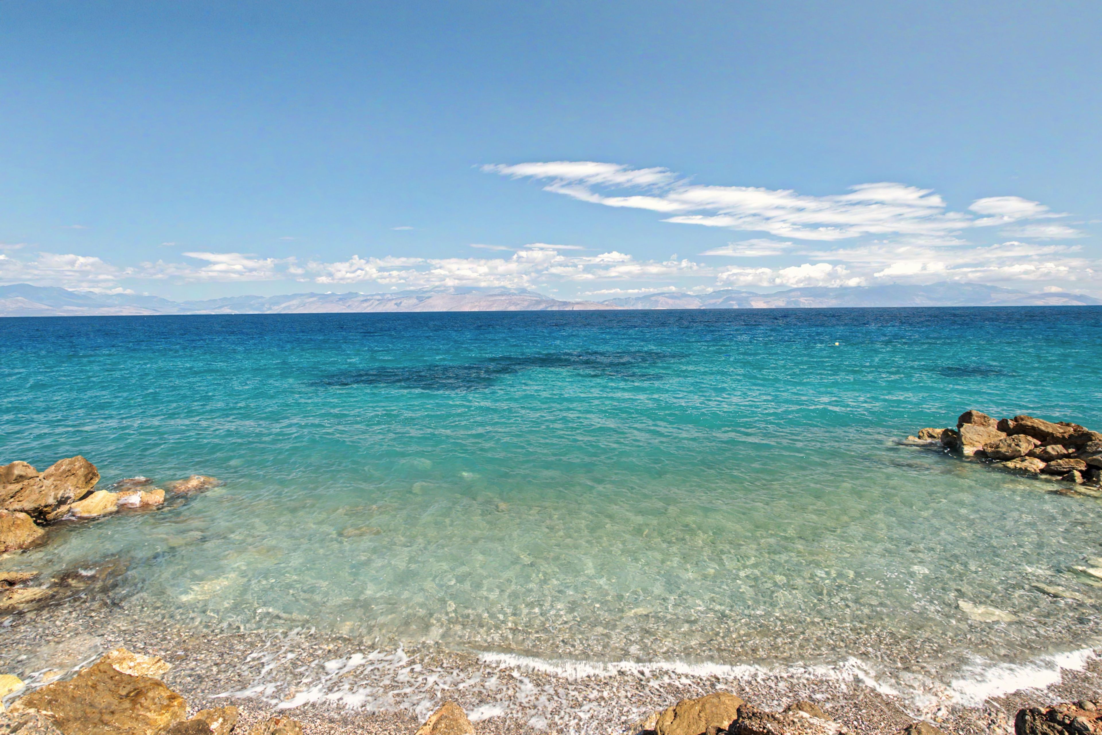 A clear coastal view with rocky shores and calm sea.