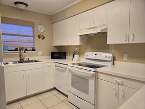 A kitchen with white cabinets, a microwave, a stove, and a dishwasher. - Affordable 2-bed Condo in Orange Beach, Beach Side Many Amenities Tennis villas (Orange Beach)