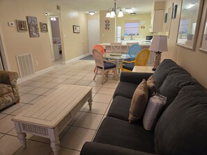 Een woonkamer met een bank, een salontafel en een eethoek met stoelen en een tafel.