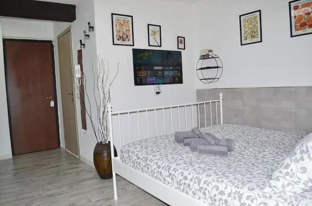 Een slaapkamer met een bed, een televisie en kunst aan de muur.
