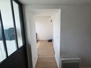 Ein schmaler Flur mit Heizkörper, Fenster und einer Tür zu einem anderen Raum.