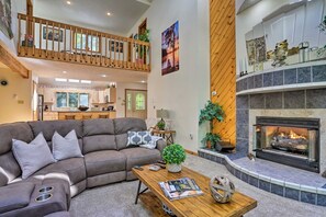 Ein modernes Wohnzimmer mit einem Ecksofa, einem Kamin und einer Holztreppe.