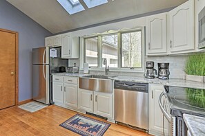 A modern kitchen with white cabinets, stainless steel appliances, and a large window. - Spacious 4-bedroom house in adorable Pocono Lake with AC (Pocono  lake)