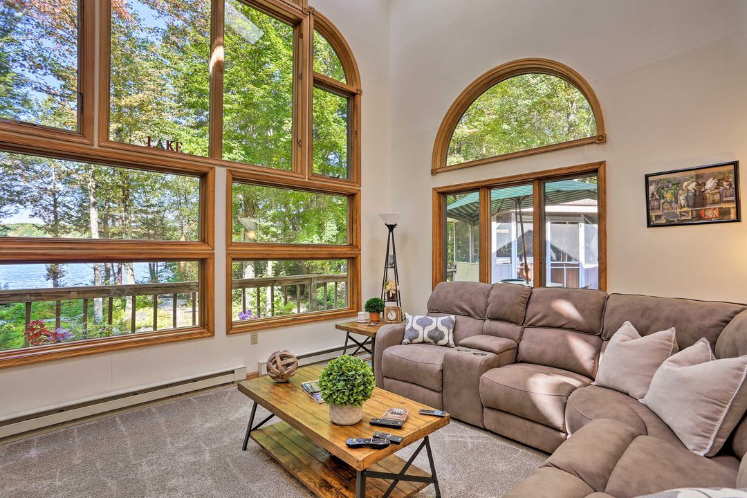 A living room with a large window overlooking a lake, a sofa, a coffee table, and a lamp.