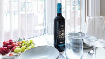Una mesa con una botella de vino, un cuenco de uvas y dos vasos de agua.