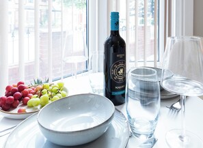 A table with a bottle of wine, a bowl of grapes, and two glasses of water.