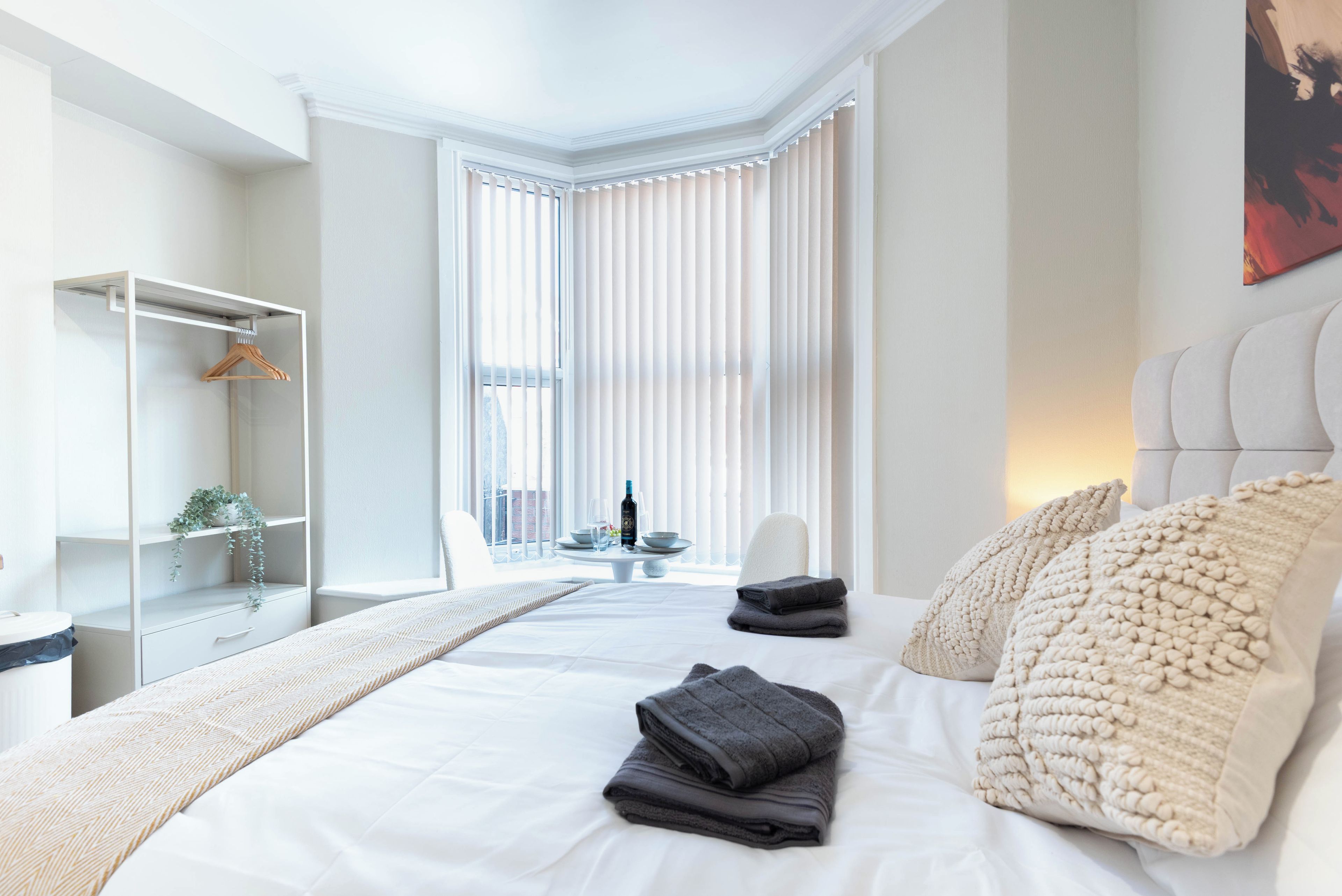 Habitación de hotel con cama, zona de estar con mesa y vistas al exterior.