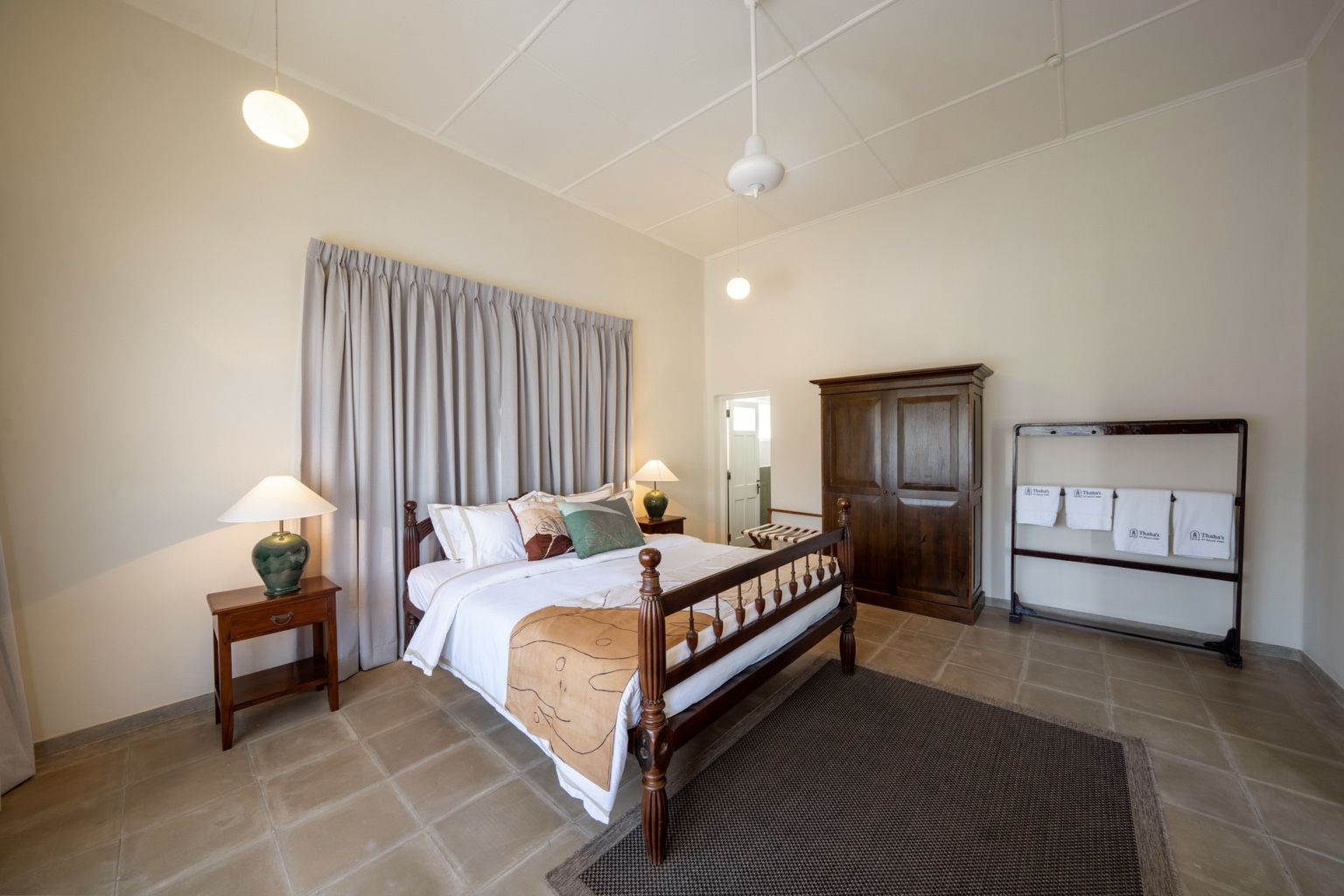 A bedroom with a bed, bedside tables, a wardrobe, and a towel rack.
