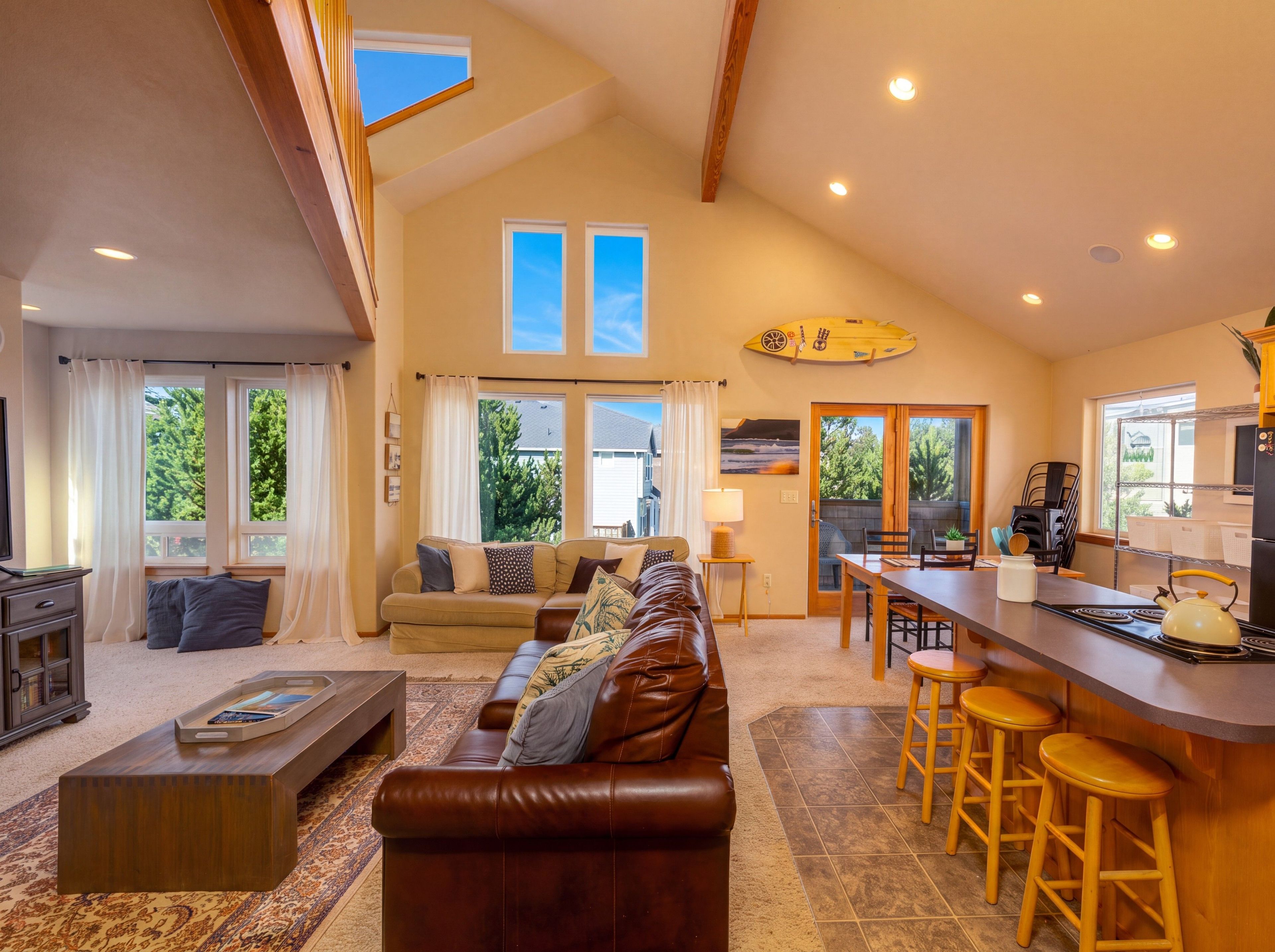 A spacious living area with a sofa, coffee table, and a dining area with stools.