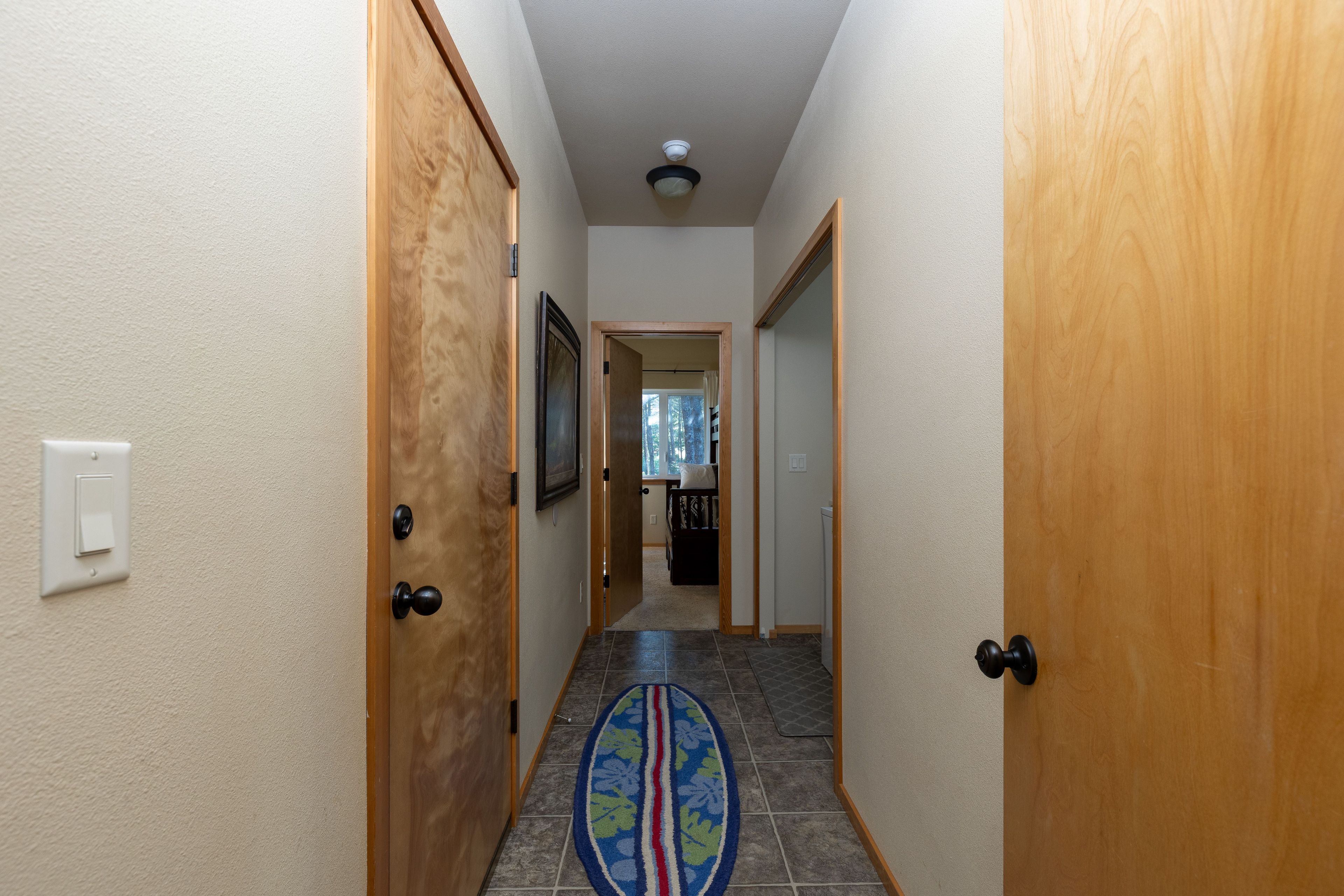 Un couloir avec des portes en bois, un sol carrelé et un tapis à motifs.