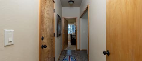 A hallway with wooden doors, a tiled floor, and a patterned rug.