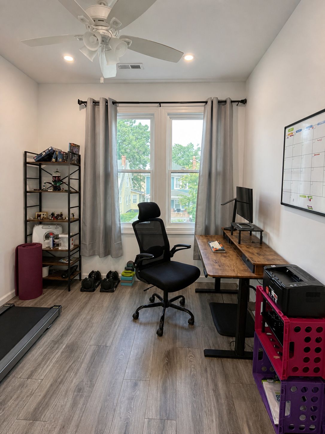 A room with a desk, chair, bookshelf, and a window with curtains.