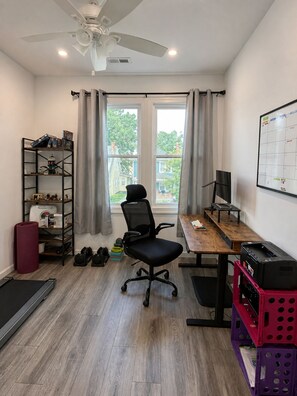 Une pièce comprenant un bureau, une chaise, une bibliothèque et une fenêtre avec des rideaux.