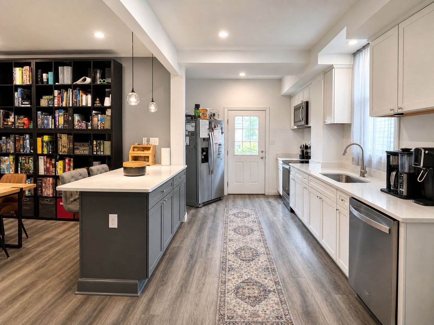 A modern kitchen with a central island, built-in appliances, and a bookshelf filled with books.