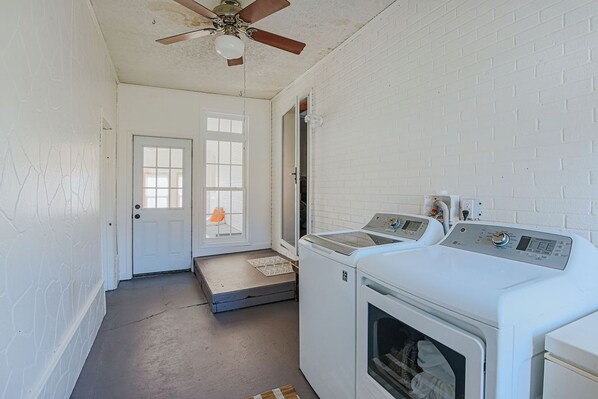 A laundry room with a ceiling fan, two washing machines, and a dryer.