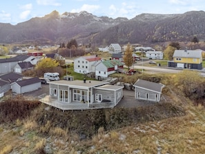 Un quartiere residenziale con case moderne, una strada asfaltata e montagne sullo sfondo.