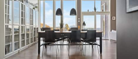 A dining area with a wooden table, black chairs, and pendant lights.