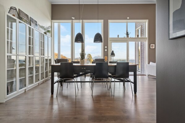 A dining area with a wooden table, black chairs, and pendant lights.