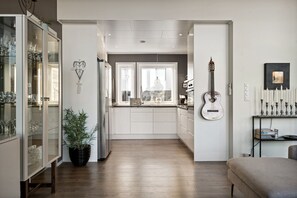 Une cuisine moderne avec des meubles blancs, un îlot central et une guitare accrochée au mur.